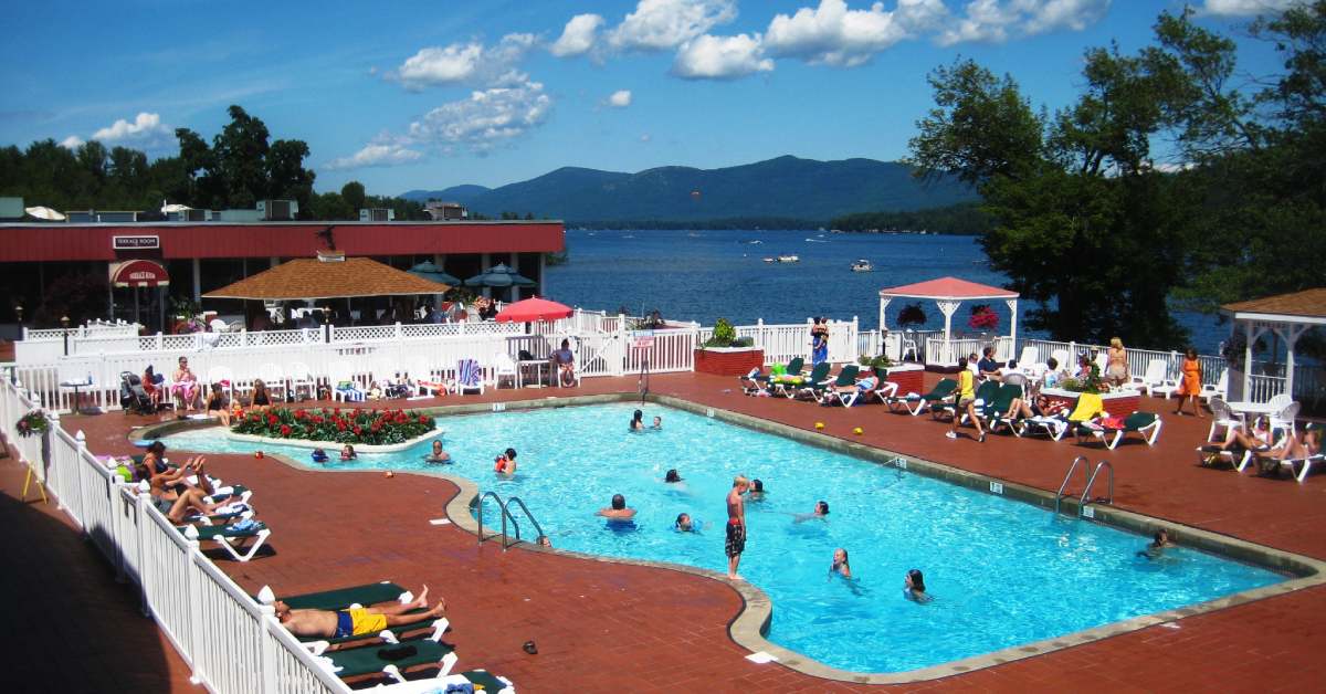 people in a hotel pool by a lake