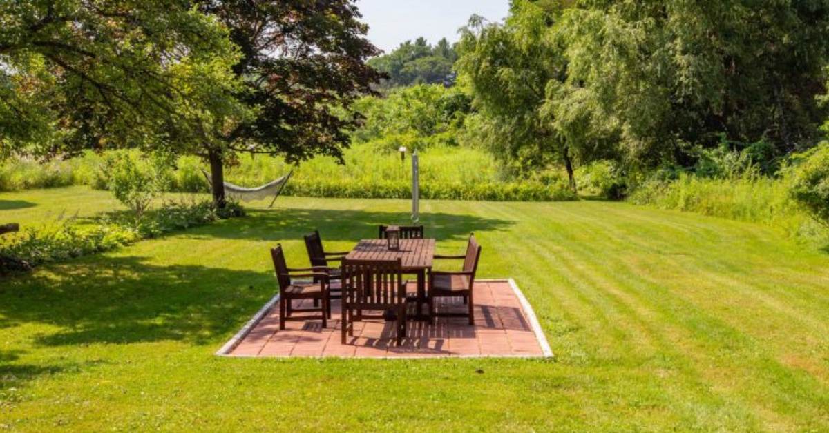 picnic table and chairs in the center of a grassy lawn