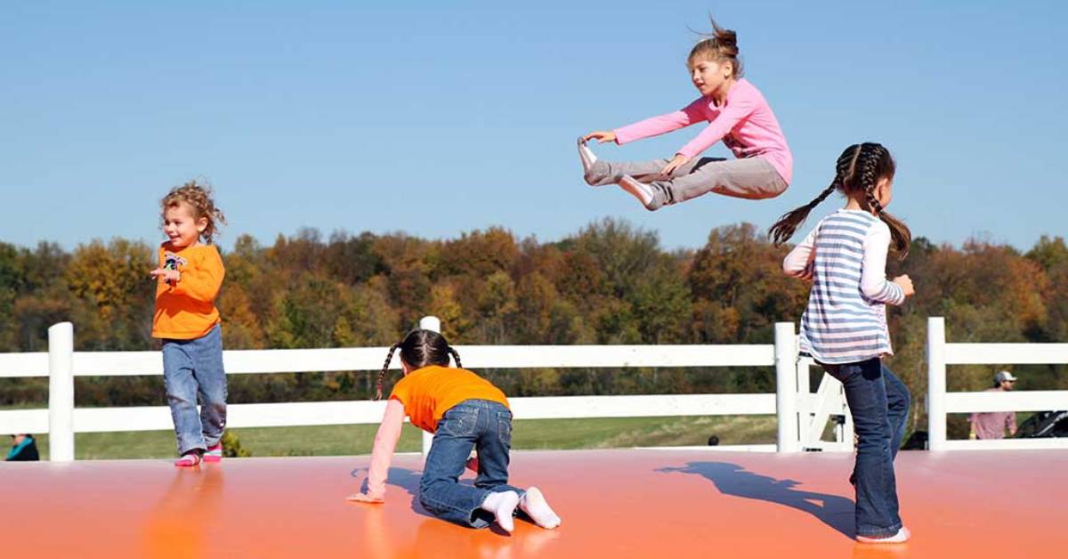 four kids on a large outdoor jump pad