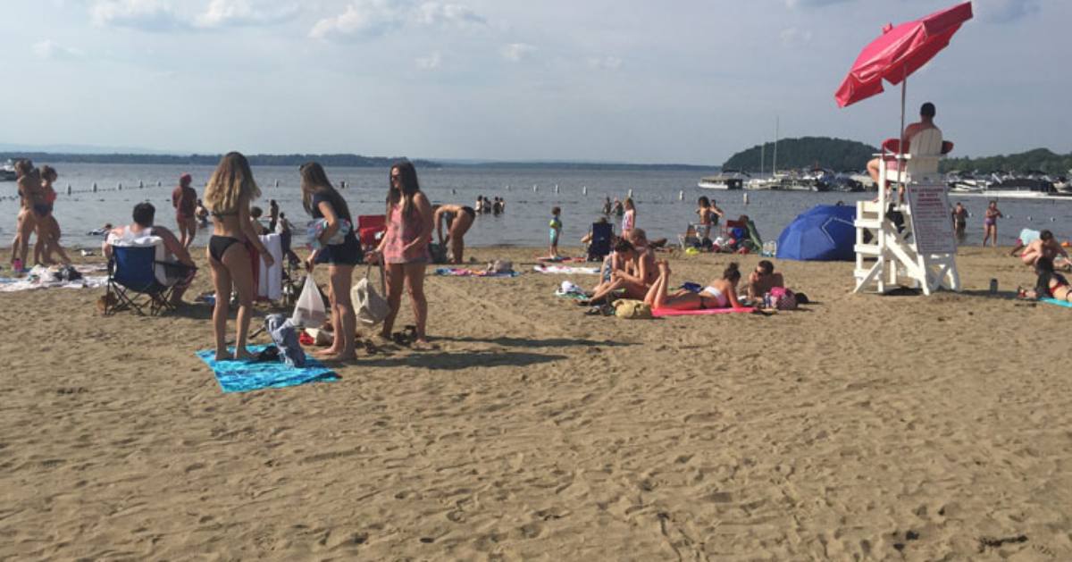 people on a sandy beach by a lake