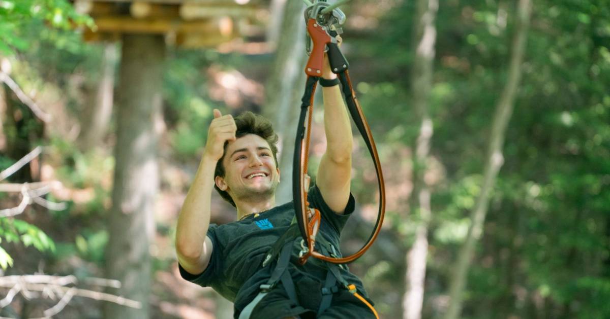 teen boy gives thumbs up while ziplining