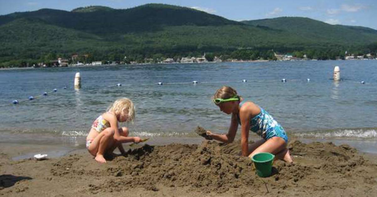 two girls build a sand castle on a beach