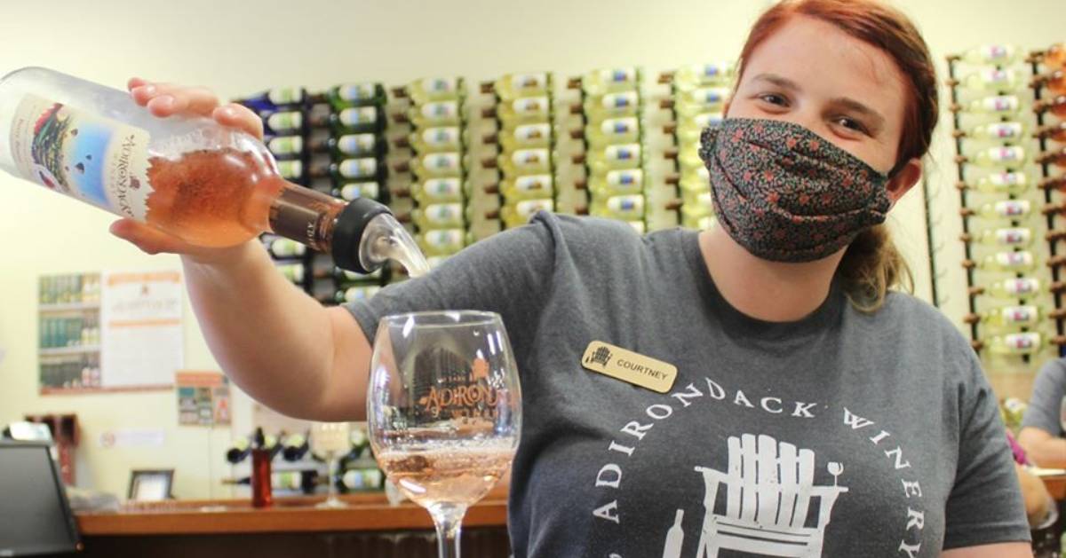 masked woman pouring wine