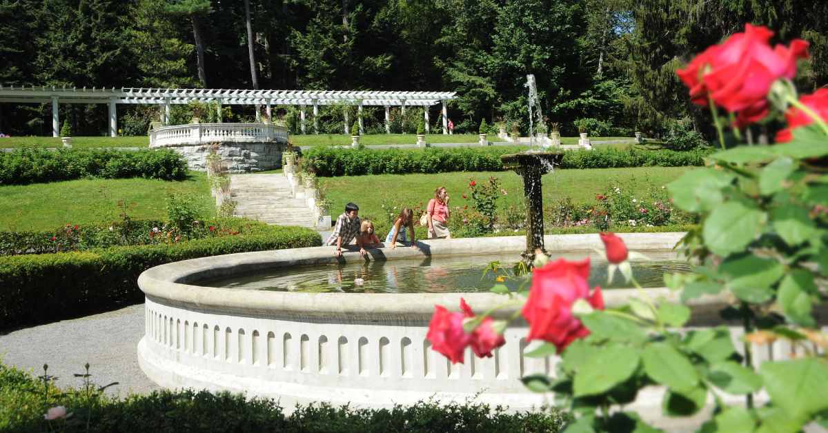 three kids and a woman by a fountain in a garden area