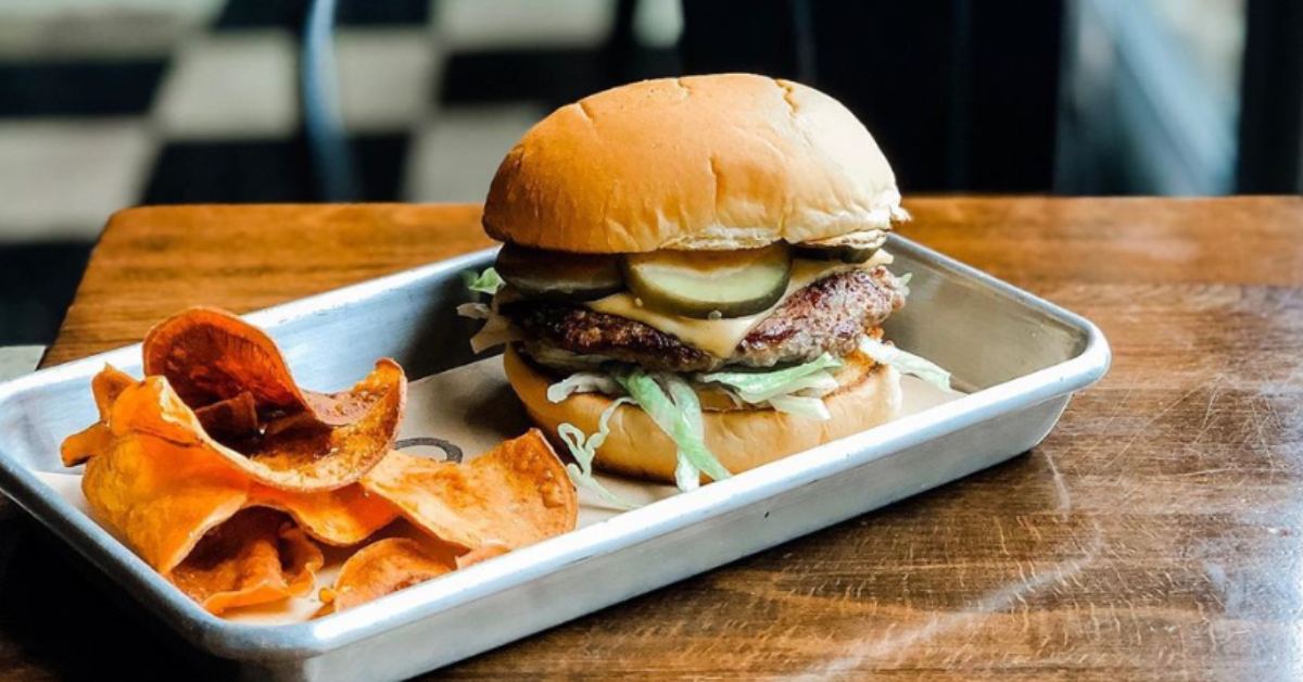 a cheeseburger and potato chips on a tray