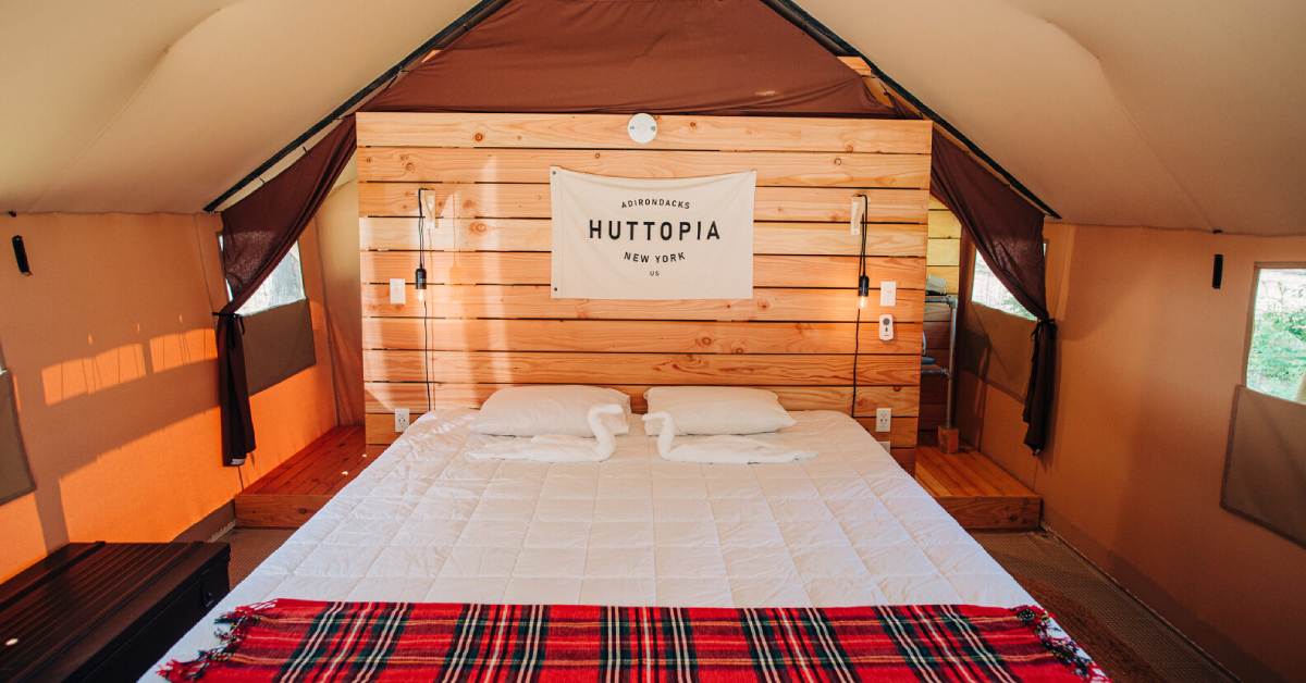 large bed in a glamping tent with a huttopia adirondacks sign