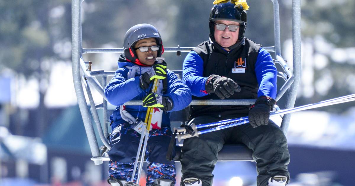 a child and a volunteer riding a ski lift at double h ranch