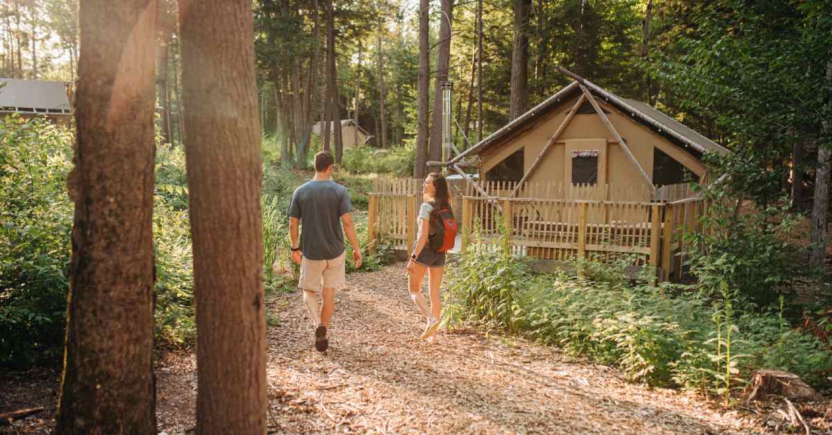 man and woman walking toward a glamping tent