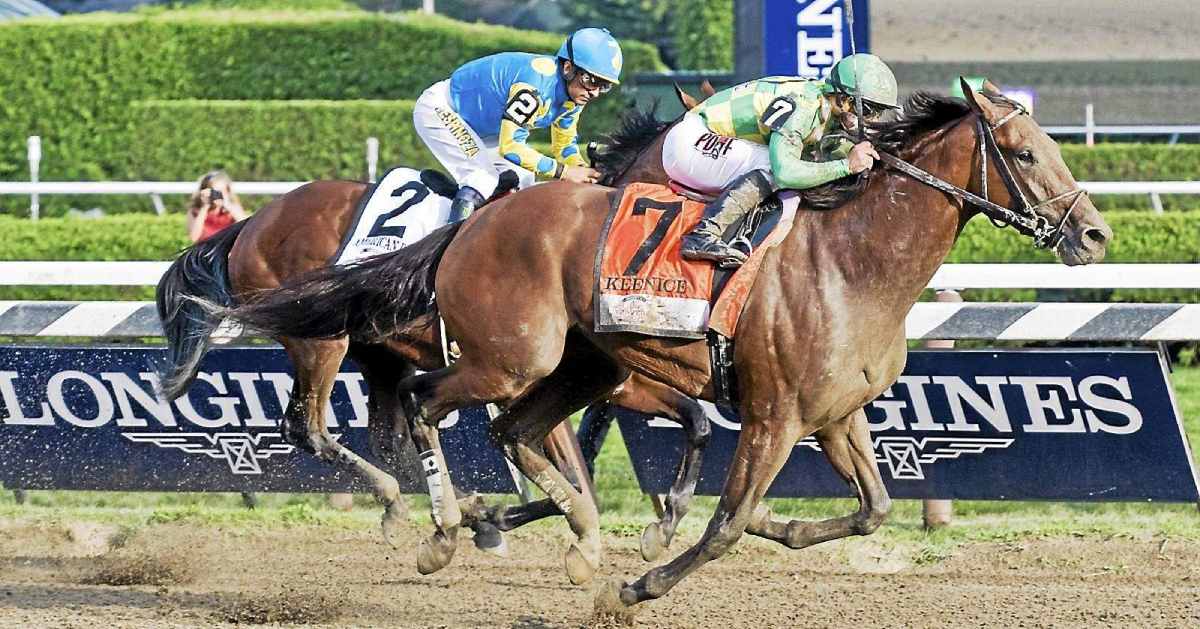 two horses racing on a dirt track