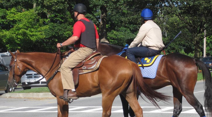 two men on horses crossing a street