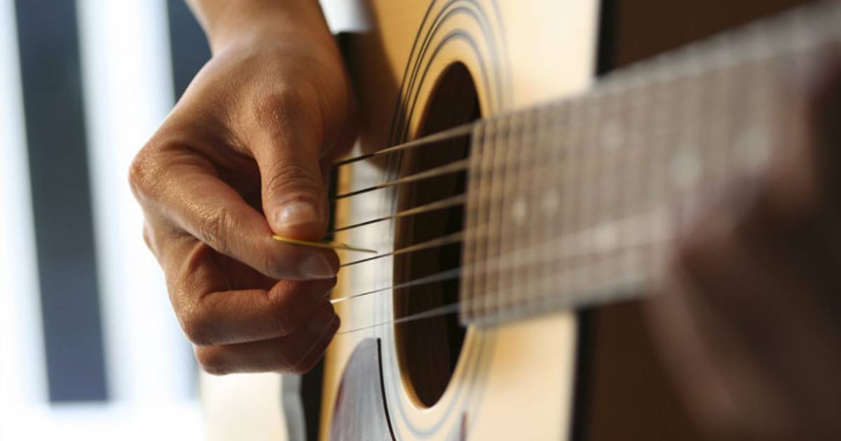 person picking an acoustic guitar