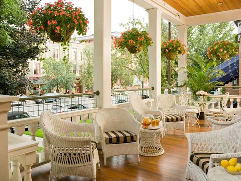 View of the porch lined with white wicker furniture at Saratoga Arms