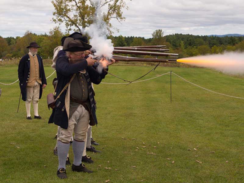Revolutionary war reenactors fire muskets at Saratoga National Historic Park