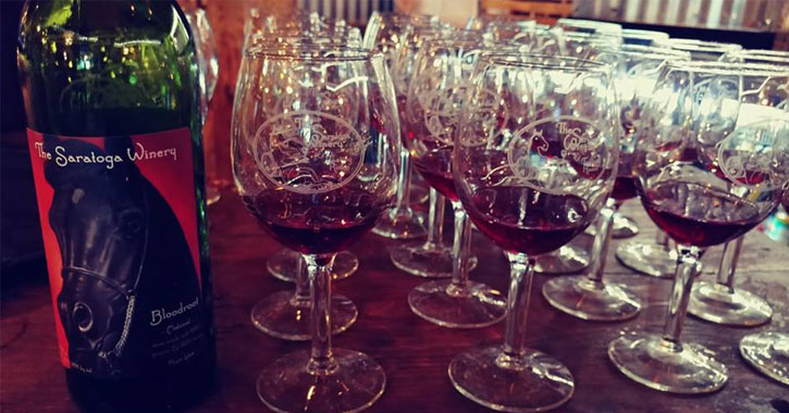 bottle of Saratoga Winery wine next to a bunch of wine glasses
