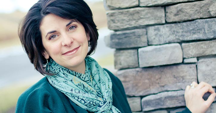 woman standing near wall and smiling for photo