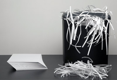 stack of paper next to a shredder with shredded paper
