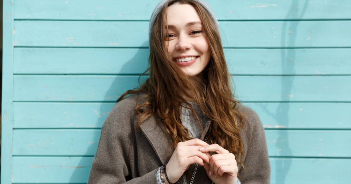 woman with a long coat on in front of a blue wall