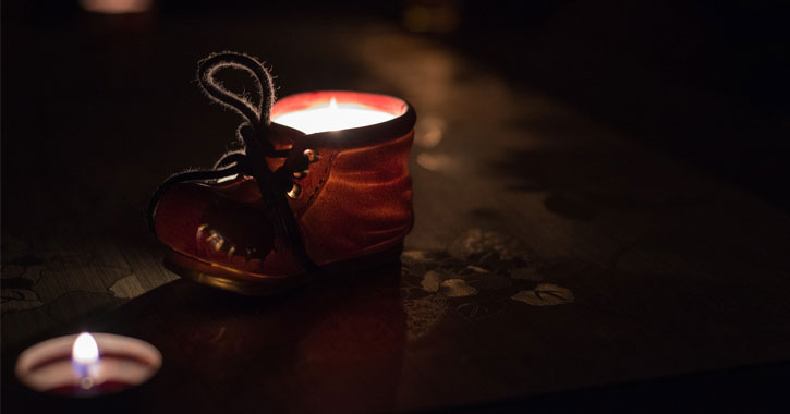 a tiny glowing shoe with a lit candle in the foreground