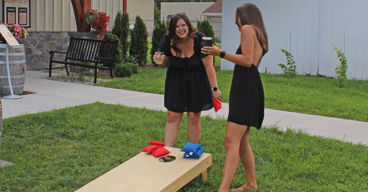 two women play cornhole