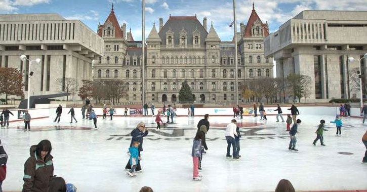people ice skating with large city building in the background