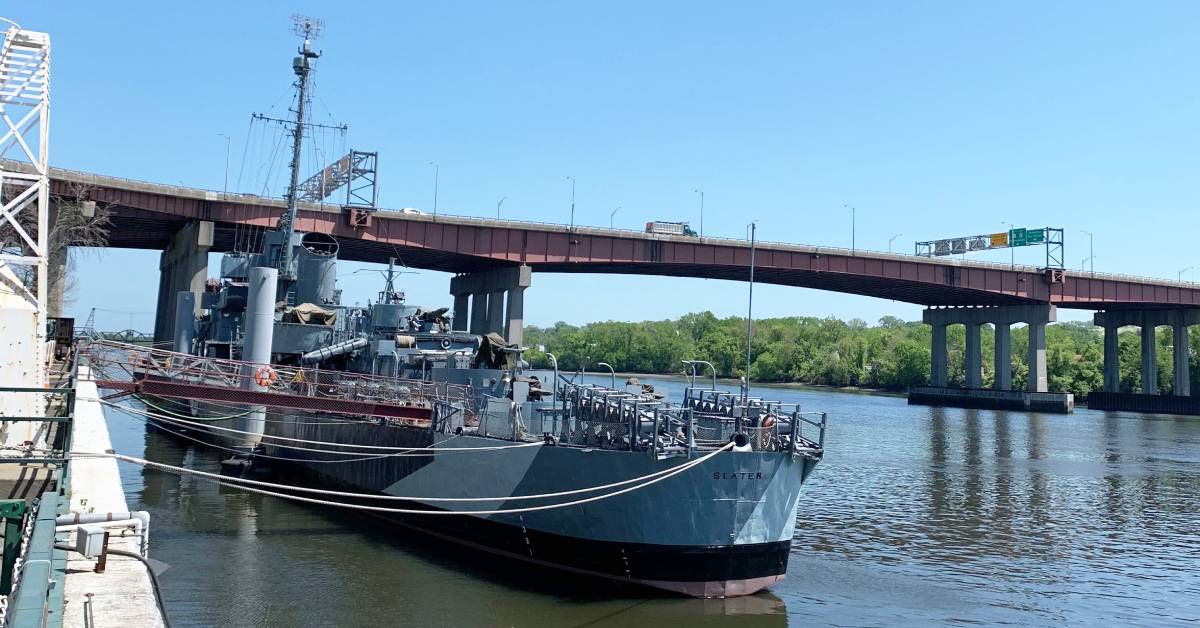 a large warship on a river docked near land