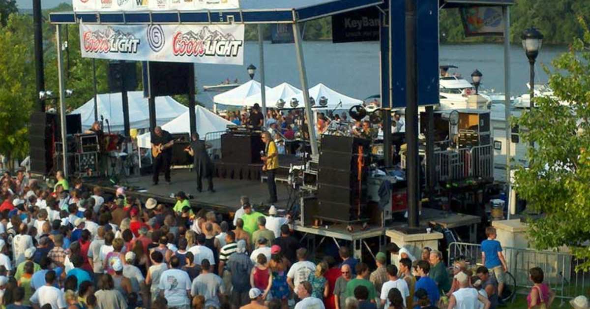 band playing on stage in front of a large crowd next to a river