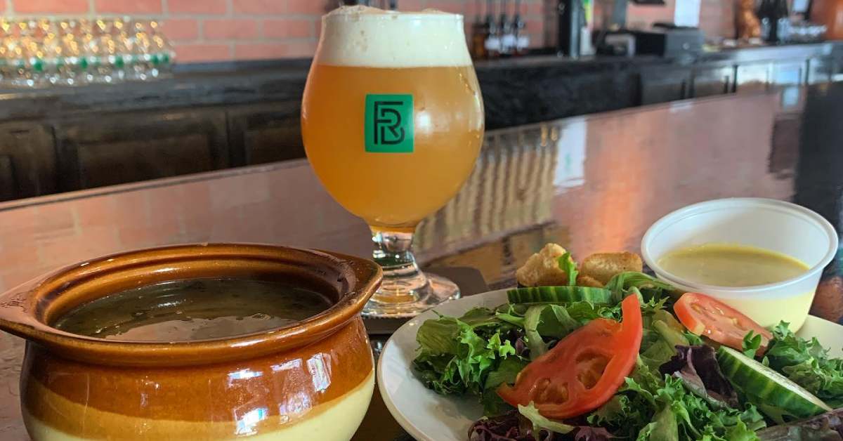 a bowl of soup, a glass of beer, and a salad