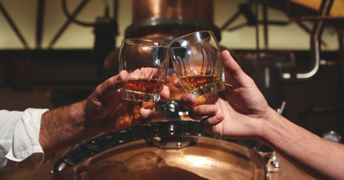 two men raising their bourbon glasses together