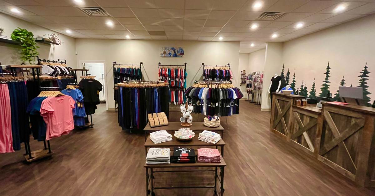 clothing store with scrubs, a table with t shirts, mugs and jewelry