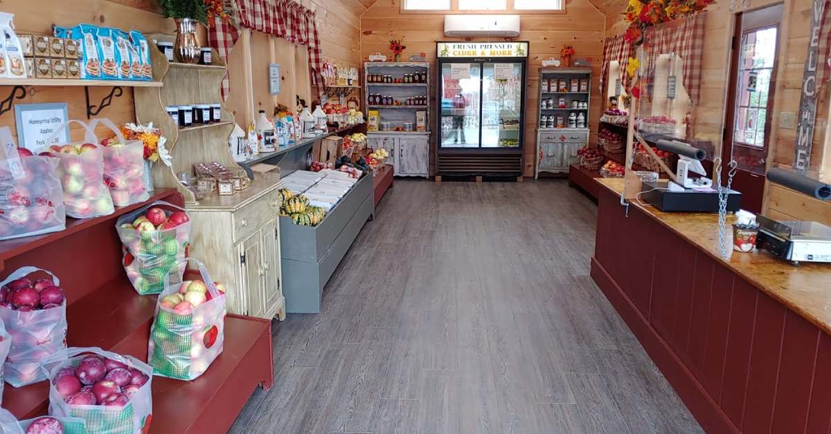 farm store with bags of apples, maple syrup, a cider fridge, and a register desk