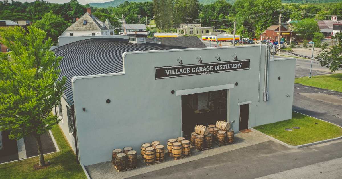 view of the exterior of the village garage distillery building with barrels in front of one entrance