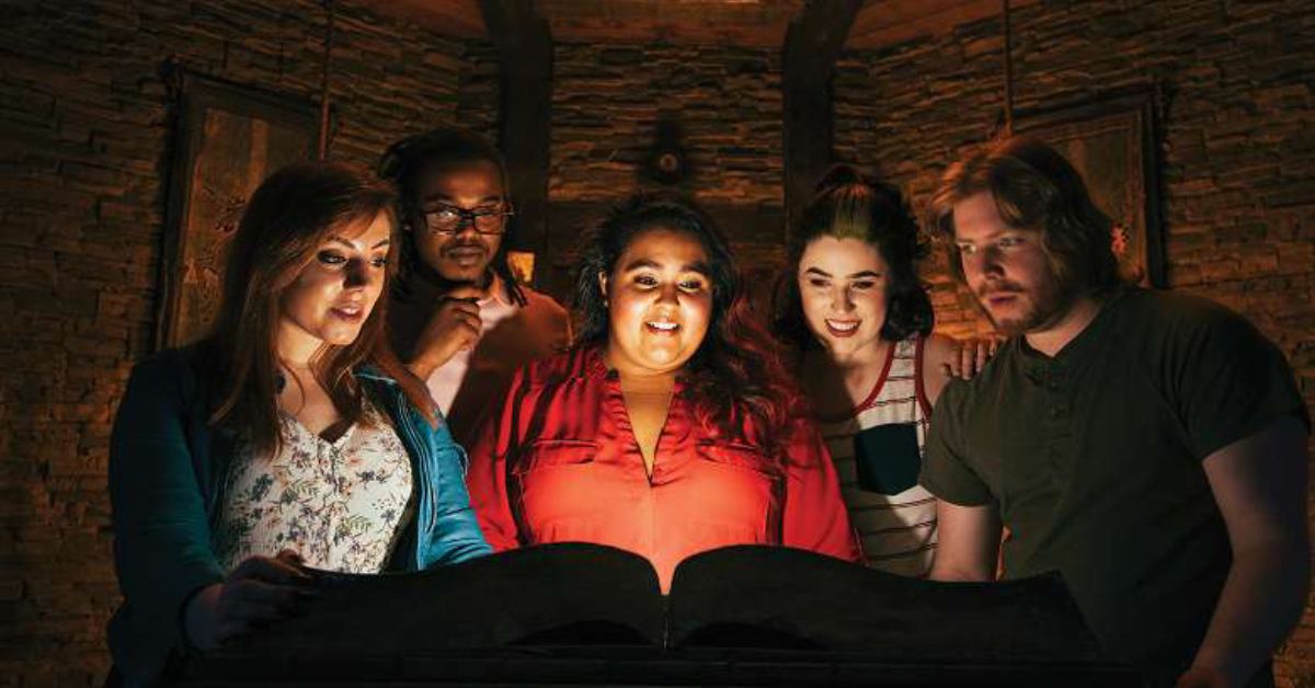 five people looking at a glowing book indiana jones style
