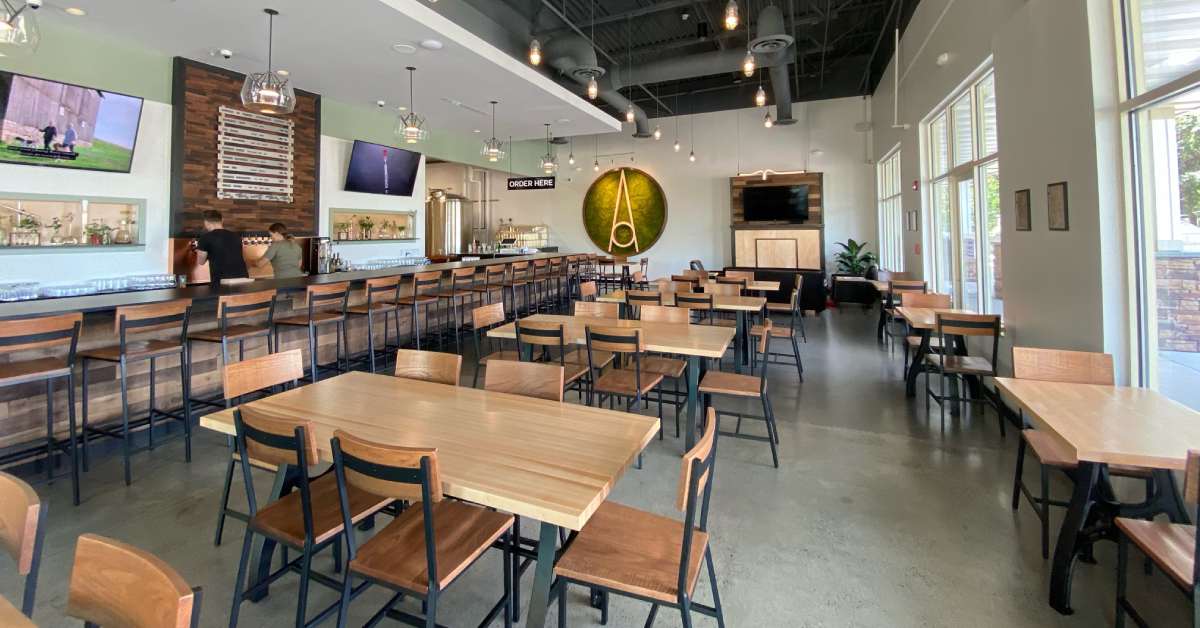 a brewery taproom with tables and chairs and a long bar