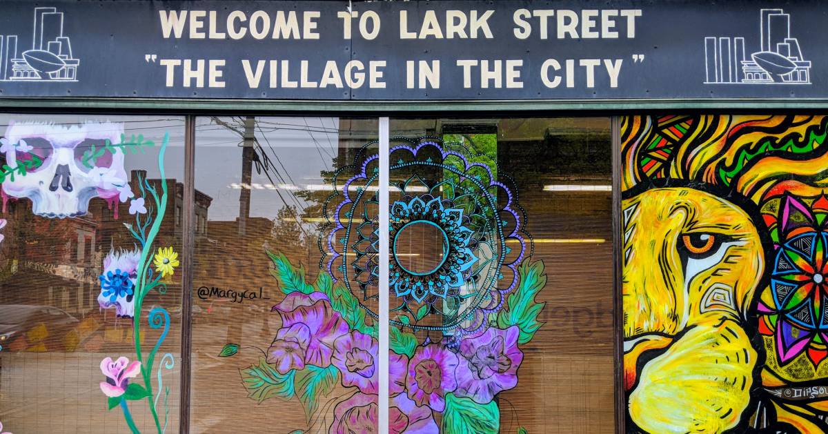 a window design on Lark Street with a sign that says Welcome to Lark Street The Village in the City