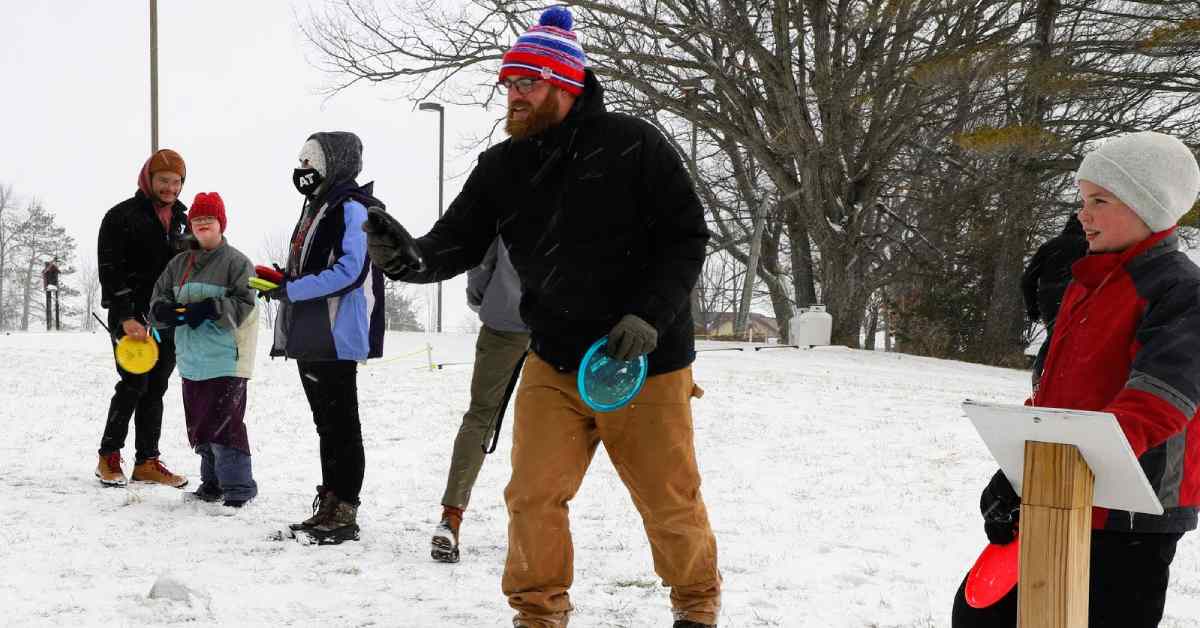people and kids playing mini disc golf in the snow