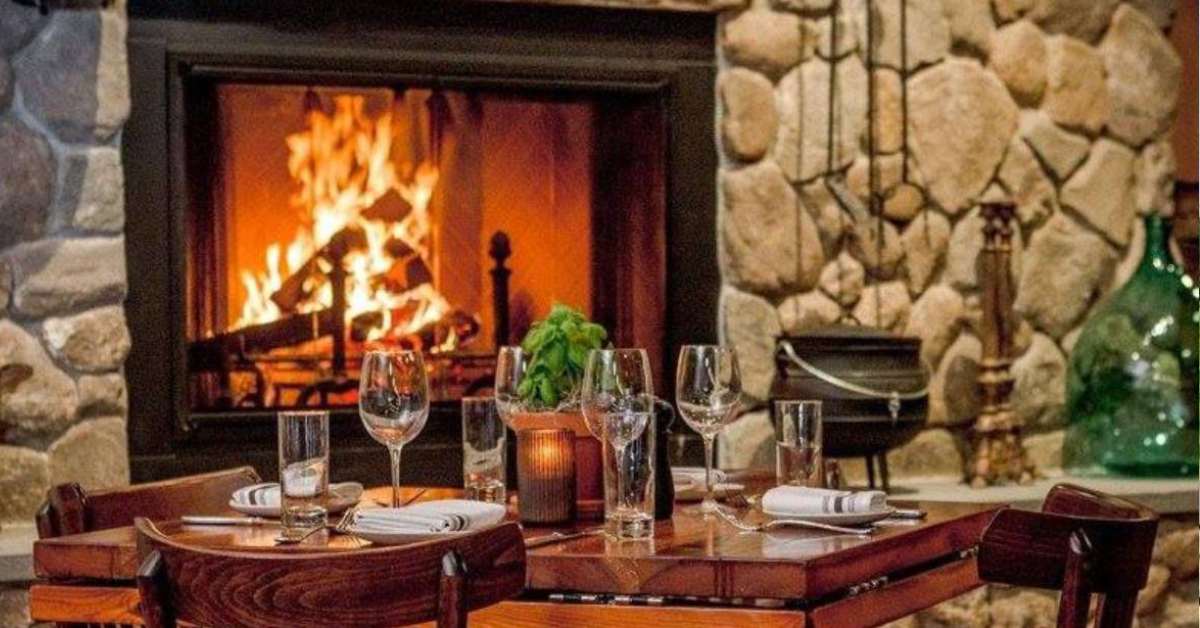 a cozy restaurant dining room with a table, chairs, and a fireplace