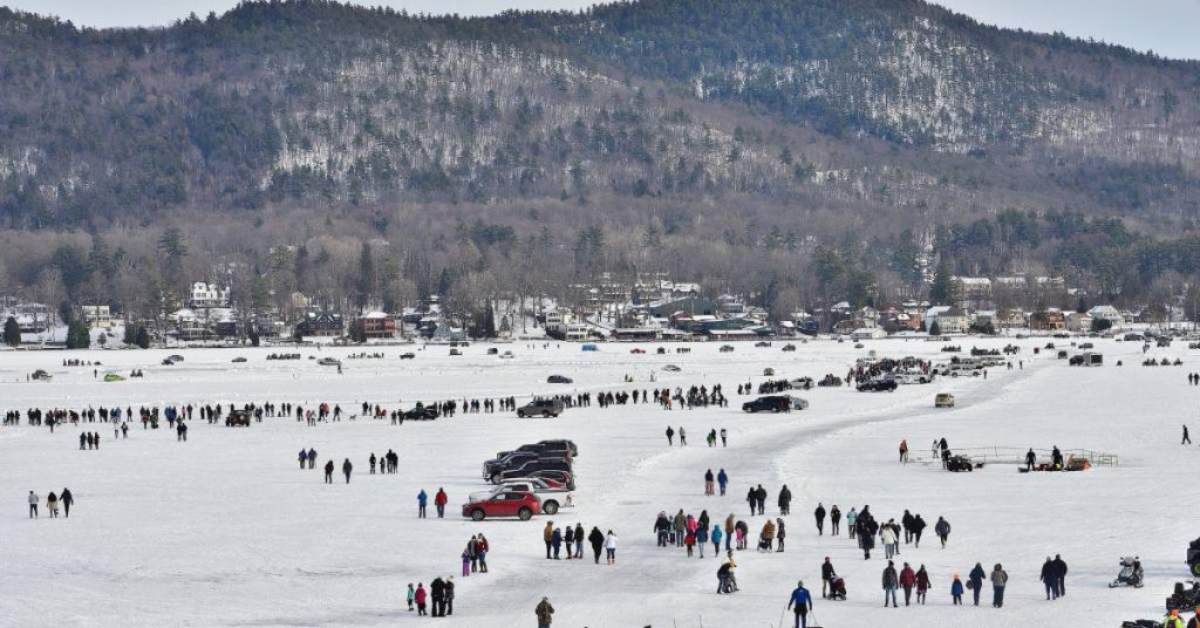 people standing out on a frozen lake for a winter carnival with mountains in the background