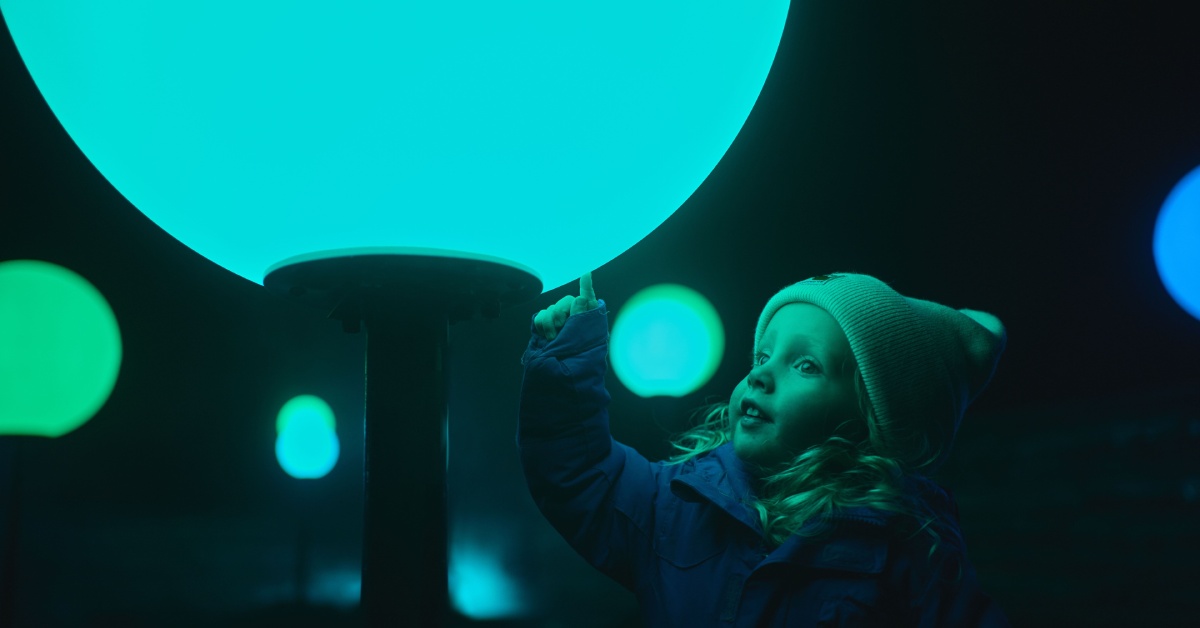 little girl touching a lit up sphere