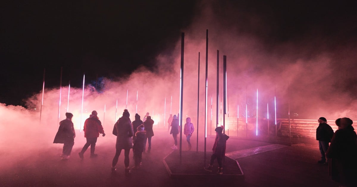 people walking through a foggy light show