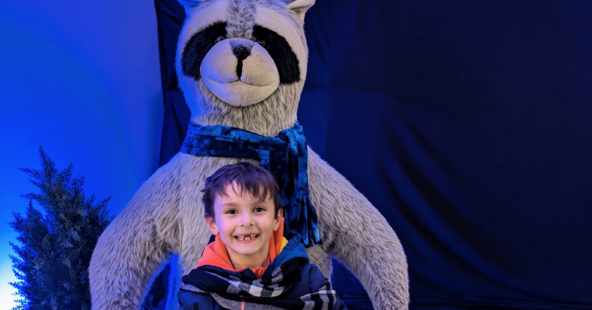 kid poses with giant stuffed raccoon