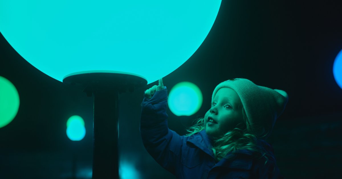 little girl in winter hat touches a full moon display