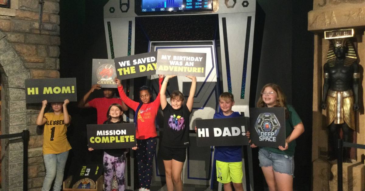 kids standing in an escape room lobby with signs