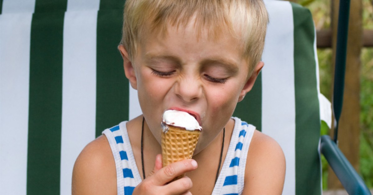 a little blond boy eating a vanilla ice cream cone