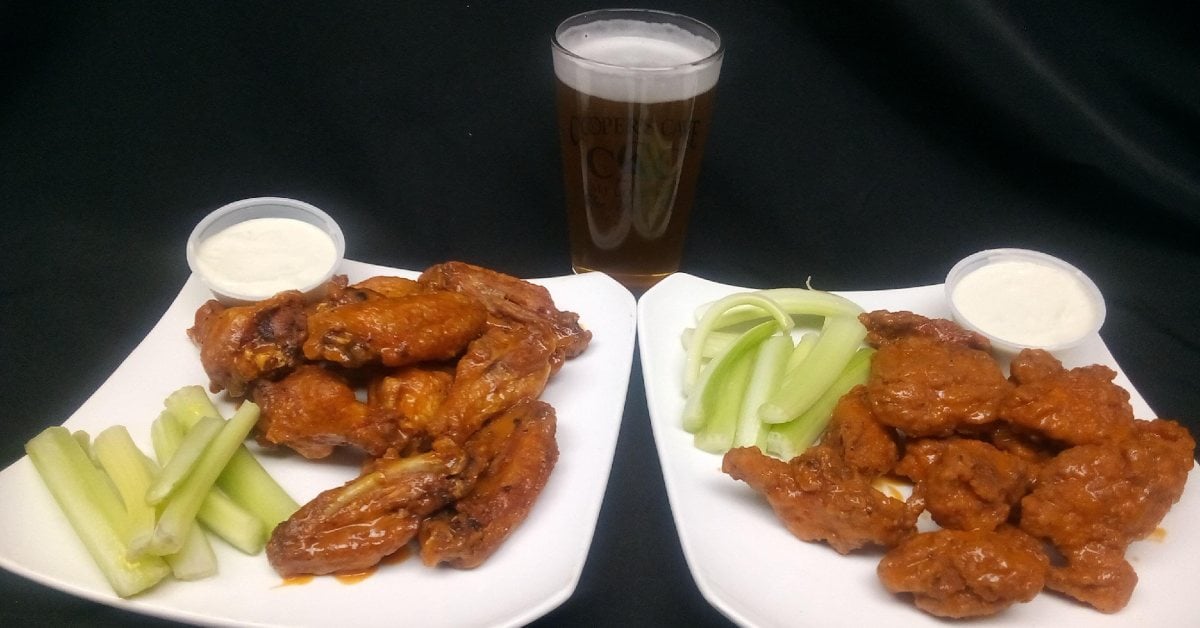 two plates of chicken wings with ranch and celery with a beer behind them