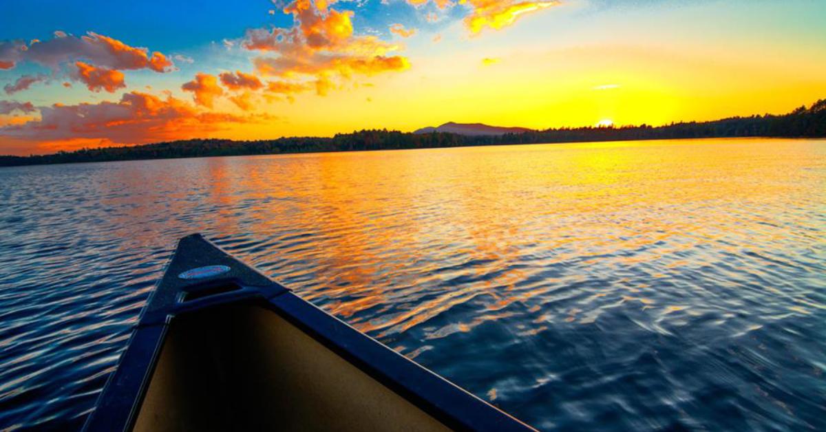 canoe on water with sunset in background