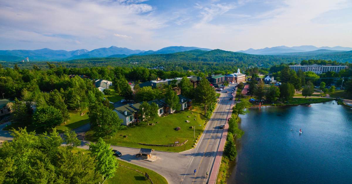 aerial view of a road along a lake with mountains in the background