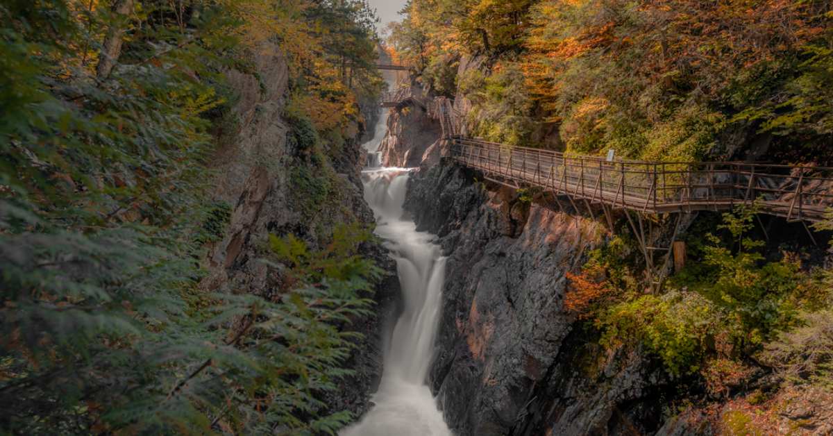 waterfall between two cliffs with walkway on the right