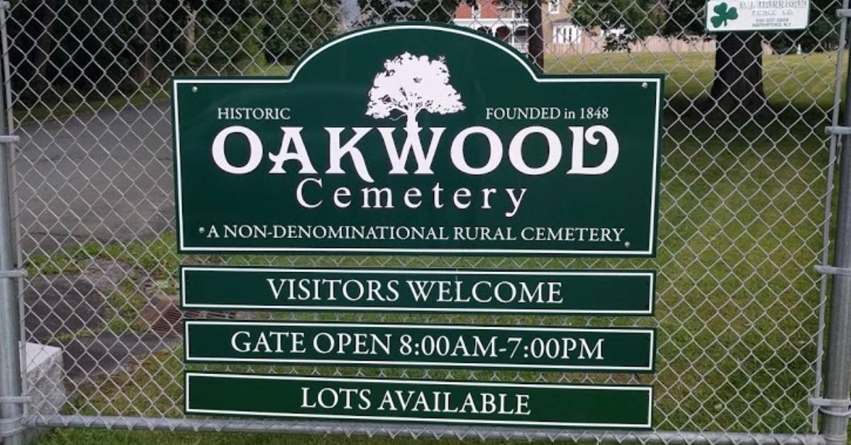 green sign on metal fence that reads historic oakwood cemetery