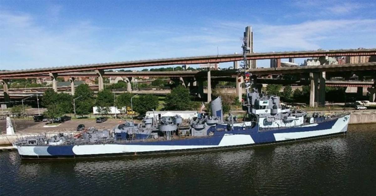 a large ship on a river with city highways in the background