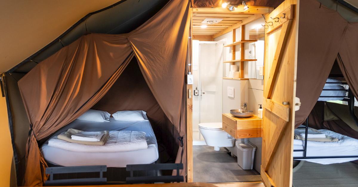 a glamping tent with beds and a bathroom
